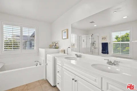 a bathroom with a tub double sink window and mirror
