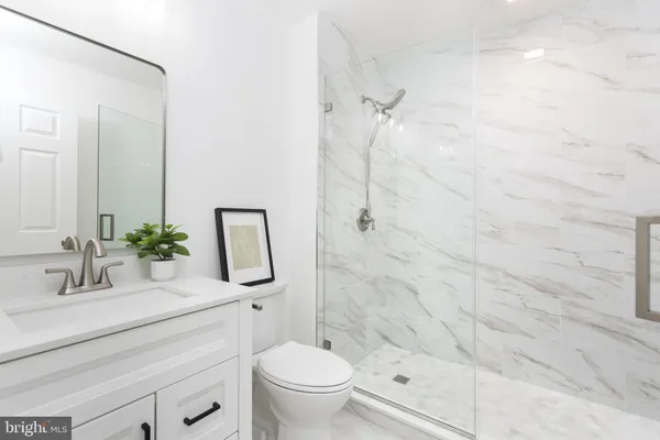 a bathroom with a granite countertop sink a toilet and shower