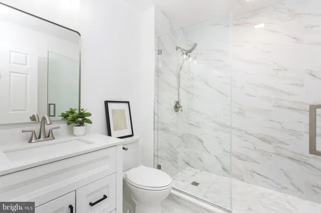 a bathroom with a granite countertop sink a toilet and shower