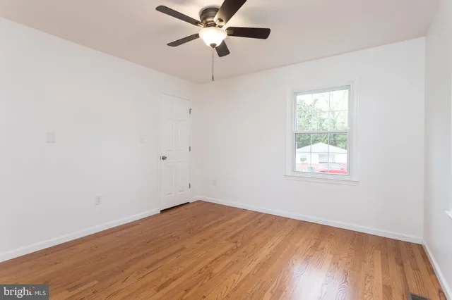 an empty room with a window and a fan