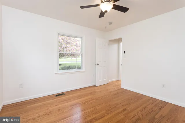 an empty room with a window and a ceiling fan