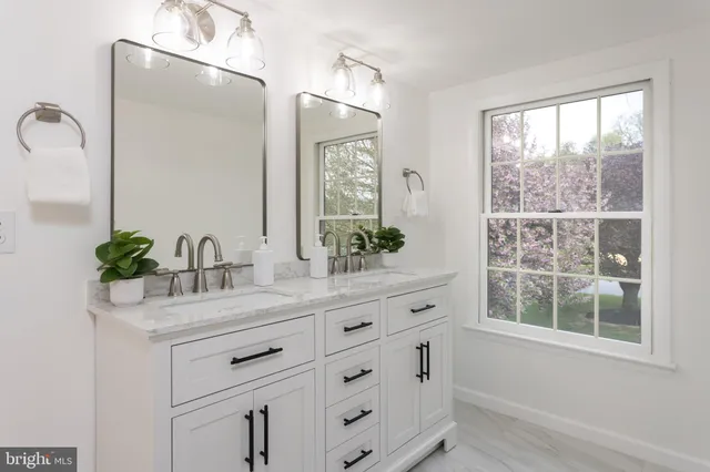 a bathroom with a granite countertop sink mirror and window
