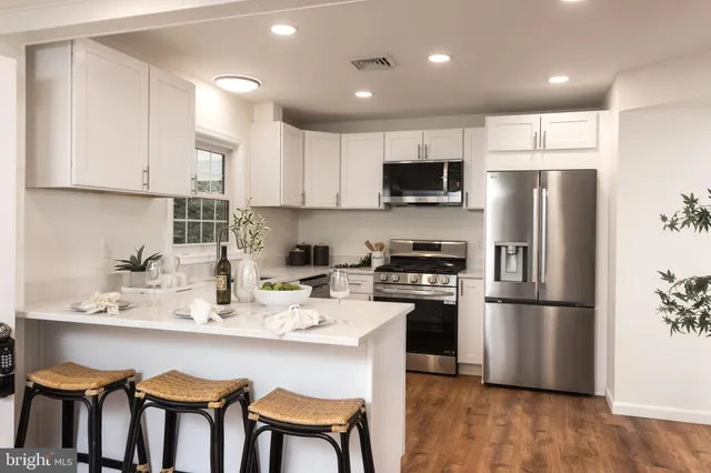 a kitchen with stainless steel appliances granite countertop a refrigerator a stove a sink a dining table and chairs