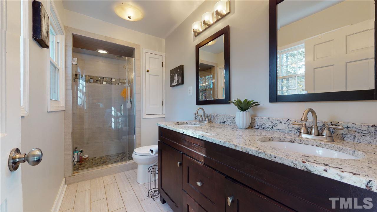 5904 Timber Ridge Drive Raleigh, NC 27609 - Photo 20 of 30 a bathroom with a granite countertop sink a toilet a shower and a mirror