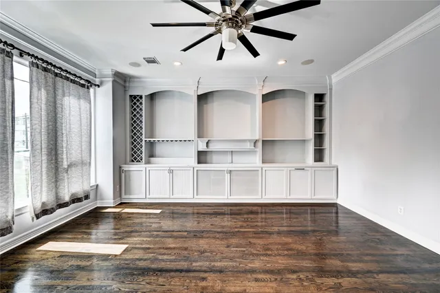 an empty room with wooden floor and a ceiling fan