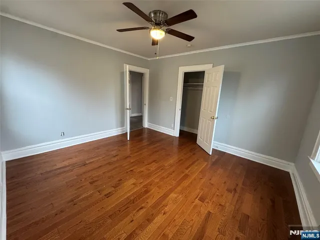 an empty room with wooden floor and a ceiling fan