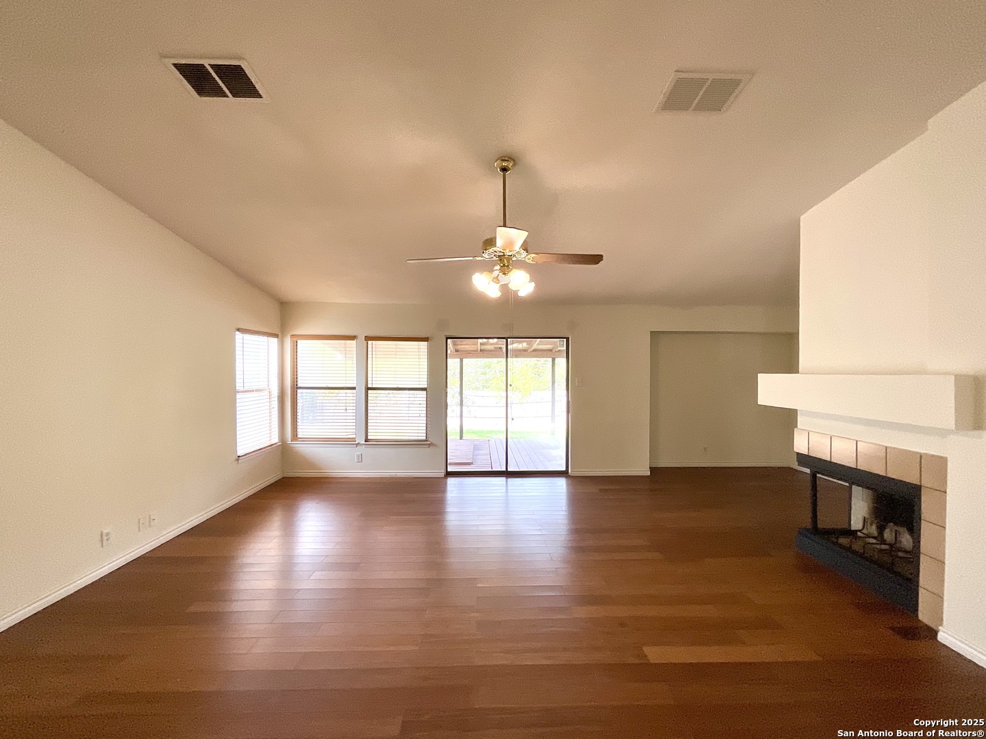 9919 Fortune Ridge Drive Converse, TX 78109 - Photo 5 of 34 an empty room with wooden floor fireplace and windows