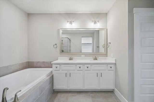 a bathroom with a granite countertop bathtub a sink and a mirror