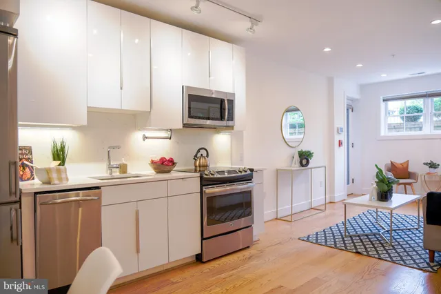 a kitchen with stainless steel appliances granite countertop a stove top oven a sink dishwasher and white cabinets with wooden floor