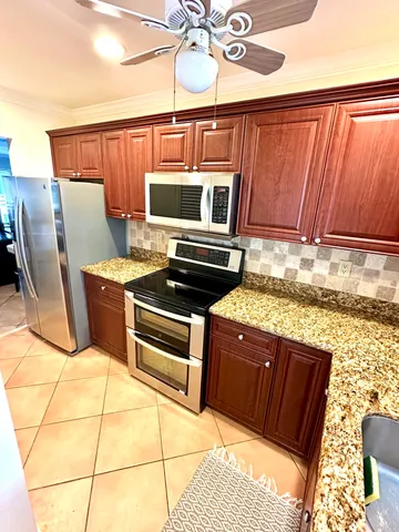 a kitchen with stainless steel appliances kitchen island granite countertop a stove top oven a dining table and chairs with wooden floor