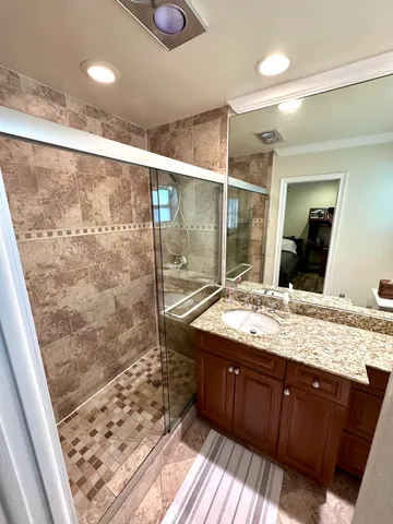 a bathroom with a granite countertop sink mirror and shower