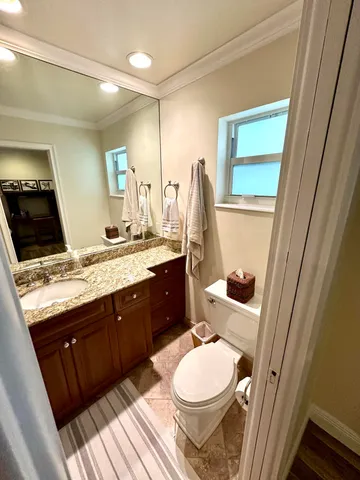a bathroom with a granite countertop toilet sink and mirror