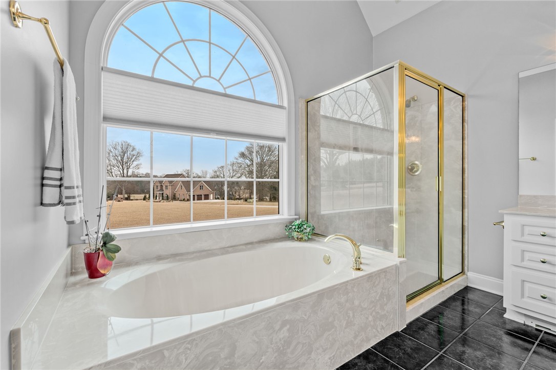 100 Farm Terrace Court Easley, SC 29642 - Photo 30 of 47 This serene bathroom offers a luxurious soaking tub and a spacious walk-in shower with a view.