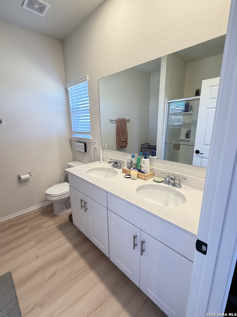 10255 Crossbuck Converse, TX 78109 - Photo 13 of 19 a spacious bathroom with a double vanity sink toilet and mirror