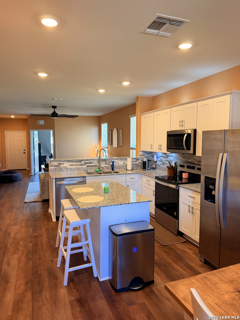 10255 Crossbuck Converse, TX 78109 - Photo 2 of 19 a kitchen with stainless steel appliances granite countertop a refrigerator a stove top oven a sink dishwasher and chairs with wooden floor