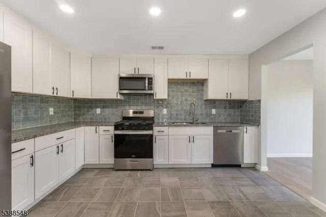a kitchen with stainless steel appliances granite countertop a stove sink and cabinets