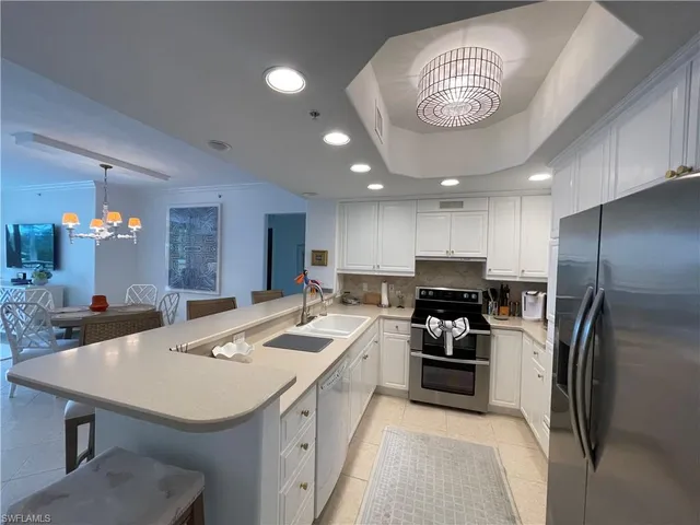a kitchen with a sink stainless steel appliances and chandelier