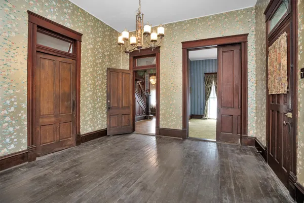 a view of a hallway with wooden floor and a chandelier