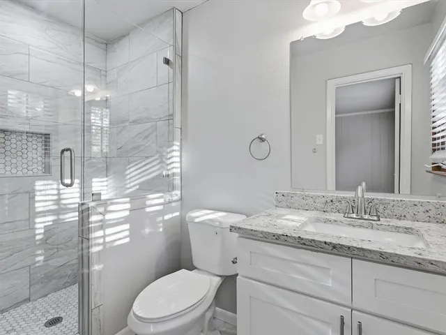 a bathroom with a granite countertop sink toilet mirror and shower
