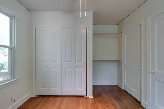a view of an empty room with wooden floor and closet area