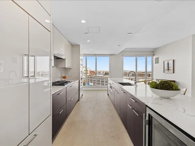 a large kitchen with a large counter top appliances a sink cabinets and a counter top space