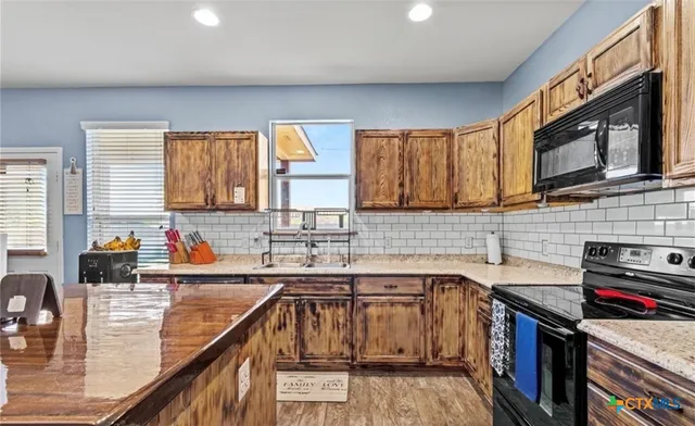a kitchen with stainless steel appliances wooden cabinets sink and a stove