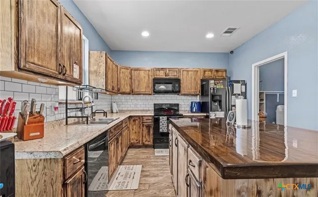 a kitchen with stainless steel appliances granite countertop a sink a stove and a wooden floors