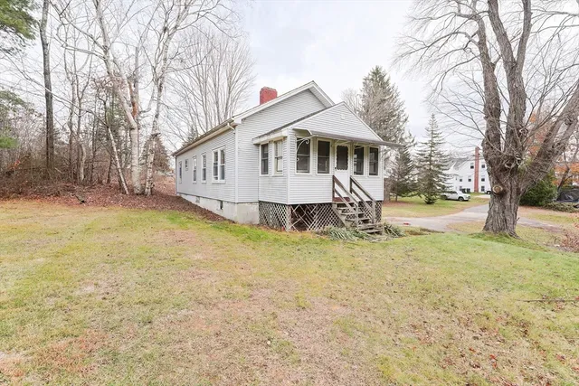 a front view of a house with a yard and large tree