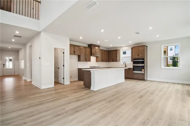 a view of a kitchen with stainless steel appliances kitchen island a large counter top and floors
