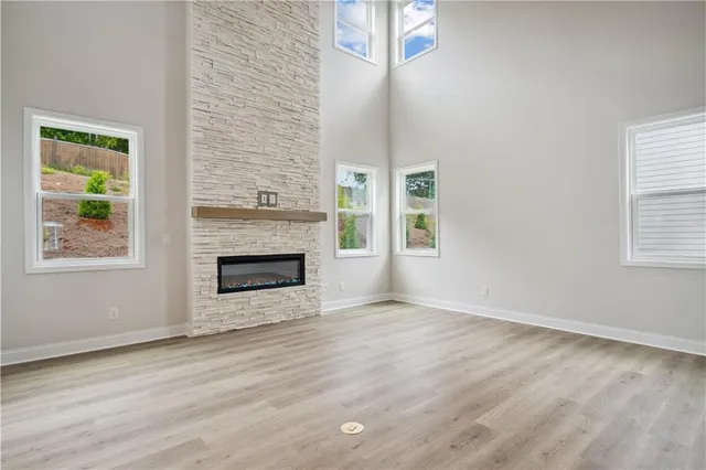a view of an empty room with wooden floor fireplace and a window