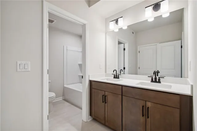 a bathroom with a double vanity sink toilet mirror and bathtub