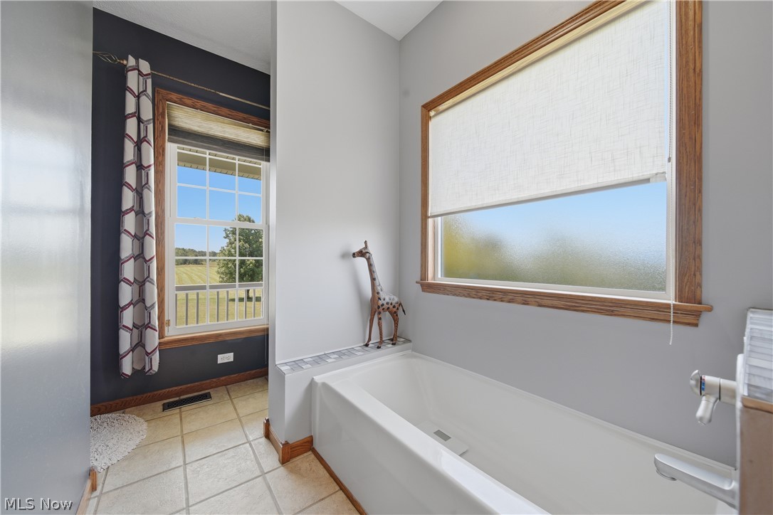 12159 Lawndell Road Southwest Beach City, OH 44608 - Photo 21 of 49 Bathroom featuring a built-in tub with a tile surround and a large window with a roller shade
