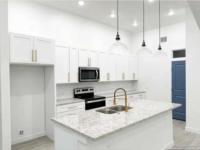 a kitchen with kitchen island a sink appliances and cabinets