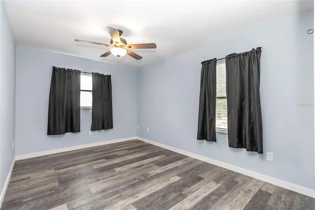 a view of a room with a ceiling fan and wooden floor