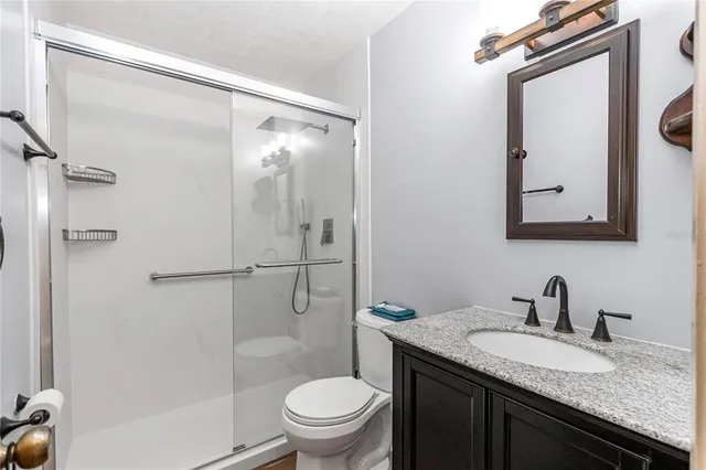 a bathroom with a granite countertop sink toilet mirror and shower