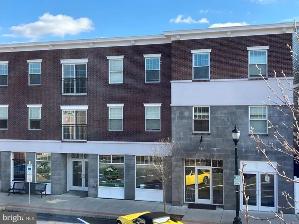 a front view of a building with glass windows and a yard