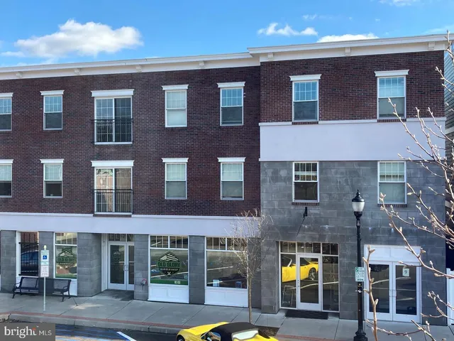 a front view of a building with glass windows and a yard