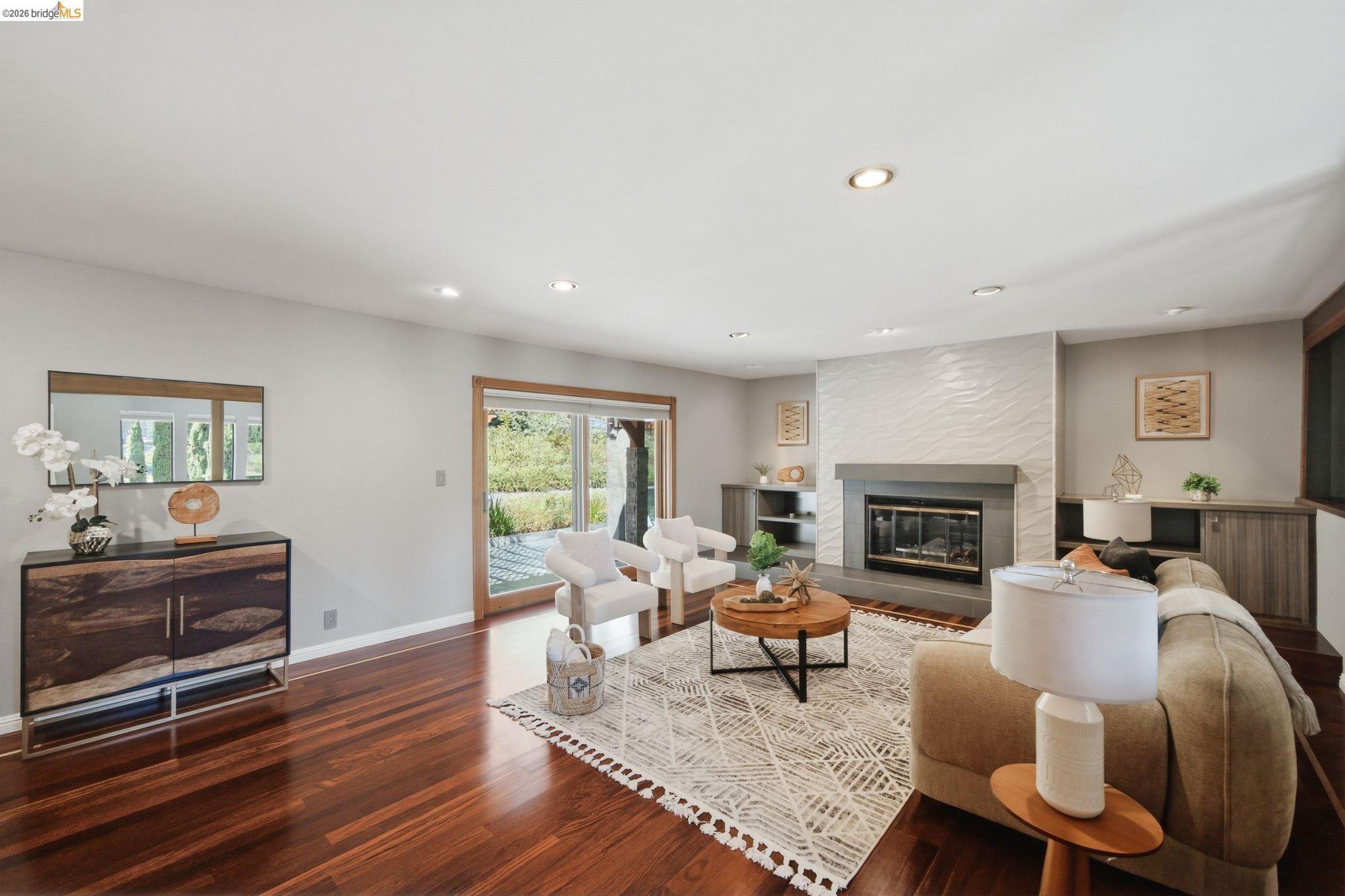 11133 Golf Links Road Oakland, CA 94605 - Photo 11 of 57 Living area featuring rich wood-finish flooring, a contemporary fireplace with a textured tile surround and stone mantel, recessed lighting, and sliding glass doors opening to the exterior
