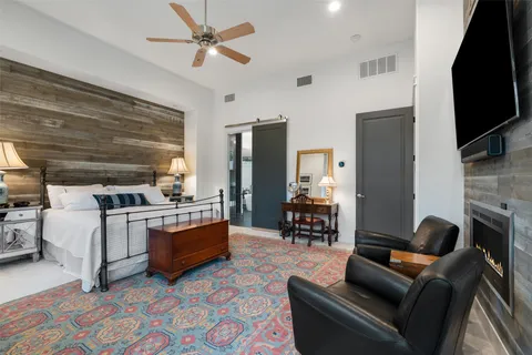 a bedroom with a bed a flat screen tv and a fireplace