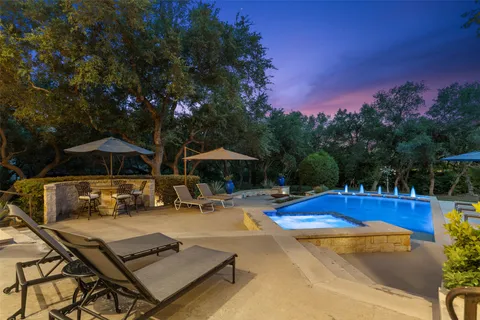a view of a swimming pool with lawn chairs under an umbrella