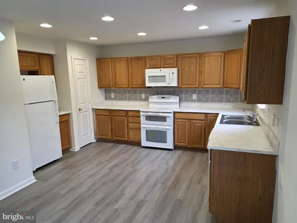 a kitchen with stainless steel appliances granite countertop a sink a stove a refrigerator with wooden cabinets and floor