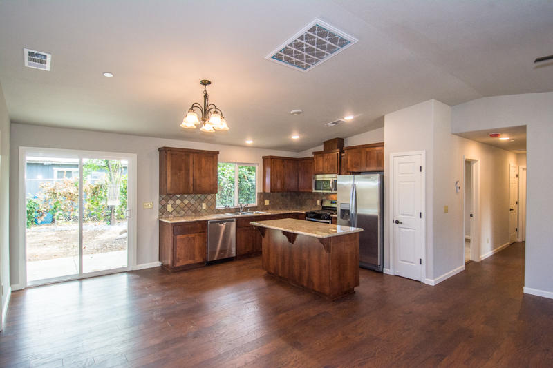 2765 Henderson Road Redding, CA 96002 - Photo 8 of 33 a kitchen with stainless steel appliances granite countertop a refrigerator a stove a sink and a dining table with wooden floor