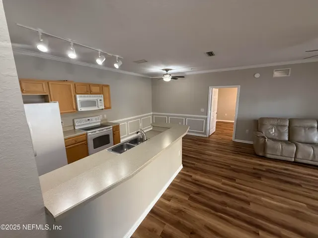 a large white kitchen with sink a microwave a stove and chairs