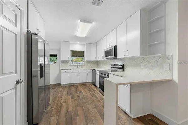 a kitchen with stainless steel appliances granite countertop a sink refrigerator and cabinets