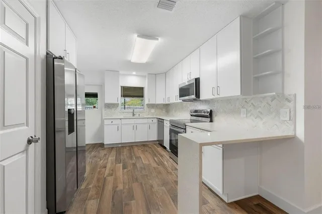 a kitchen with stainless steel appliances granite countertop a sink refrigerator and cabinets