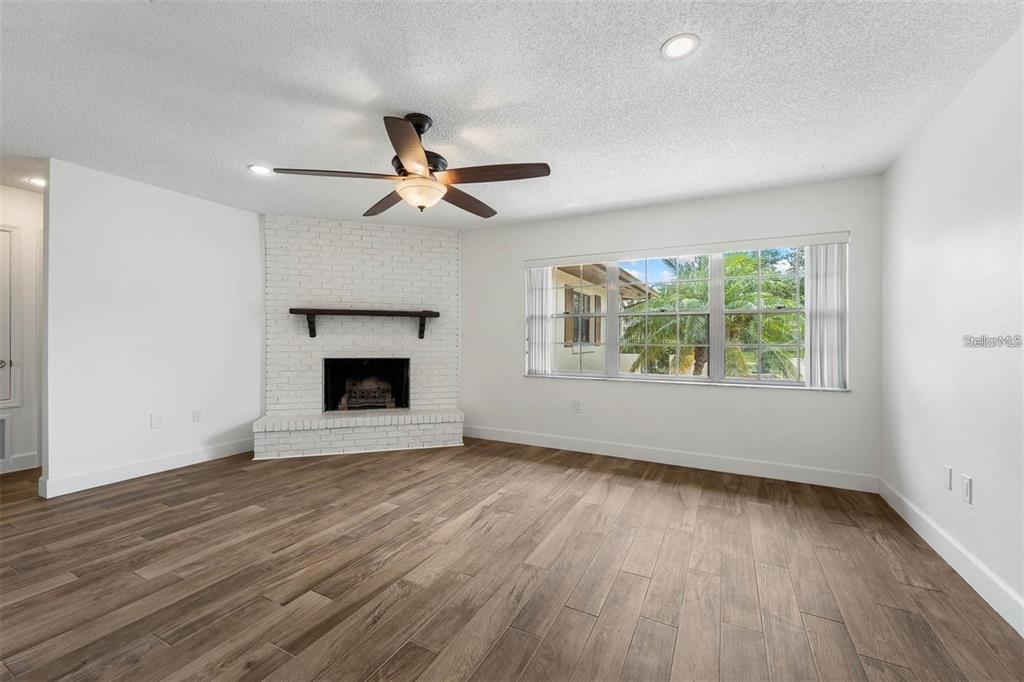 8323 Banyan Boulevard Orlando, FL 32819 - Photo 4 of 20 an empty room with wooden floor chandelier fan and windows