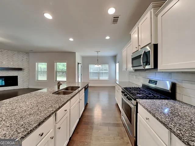a kitchen with granite countertop kitchen island stainless steel appliances a sink stove top oven and cabinets