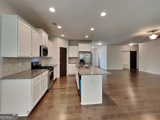 a large kitchen with stainless steel appliances granite countertop a large counter top and a stove top oven