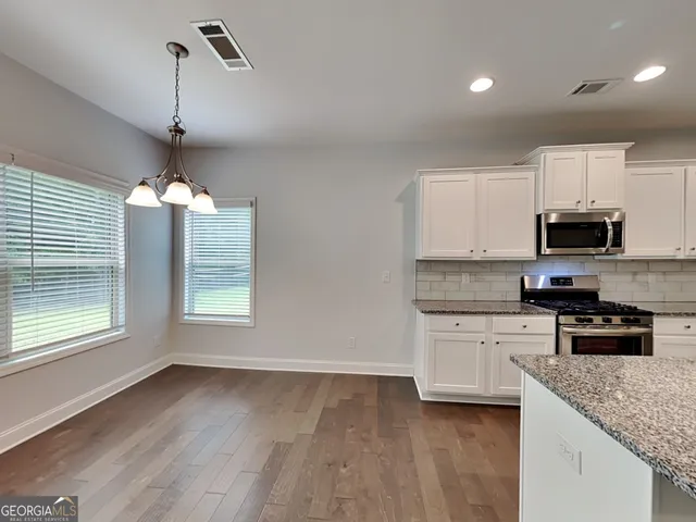 a kitchen with granite countertop a sink stainless steel appliances and window