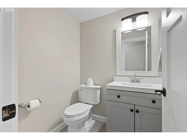 a bathroom with a toilet a sink a mirror and vanity